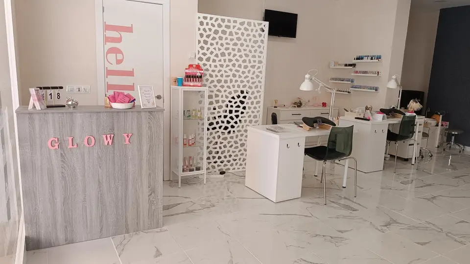 Recepción de Glowy Beauty Salon con el rótulo GLOWY y las mesas de manicura