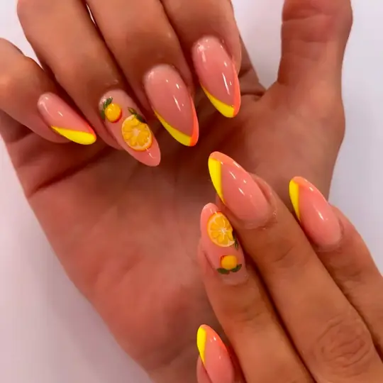 Francesa amarilla en uñas almendradas con detalles naranjas