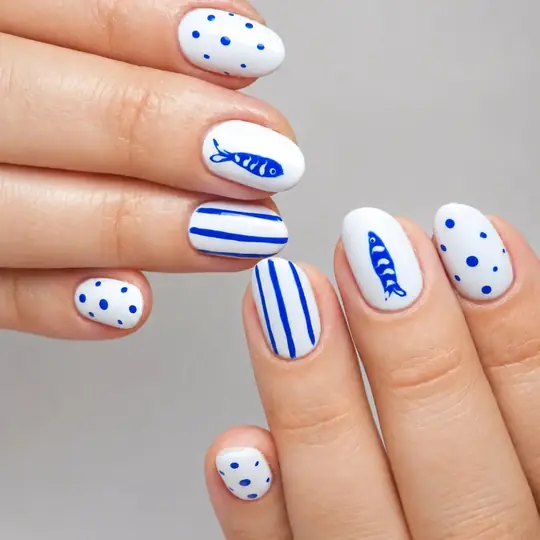 Uñas blancas con rayas, lunares y peces en azul